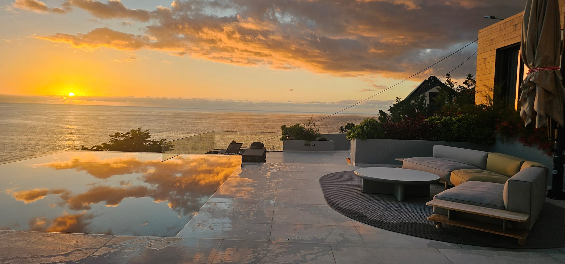 Goldene Abendsonne spiegelt sich im privaten Infinity-Pool der Villa Anjos mit Blick über den Atlantik